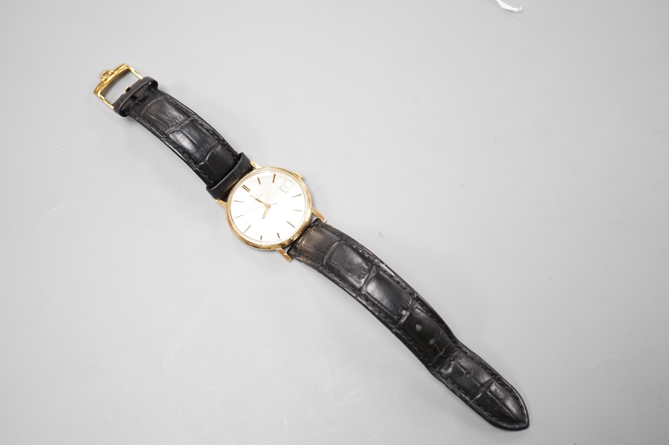 A gentleman's 9ct gold Omega manual wind wrist watch, with date aperture, on a black leather Omega strap with Omega buckle, cased diameter 33mm